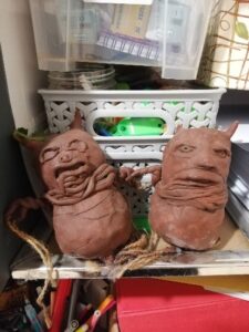 Two clay figures that are round shaped with small horns and grimacing expressions